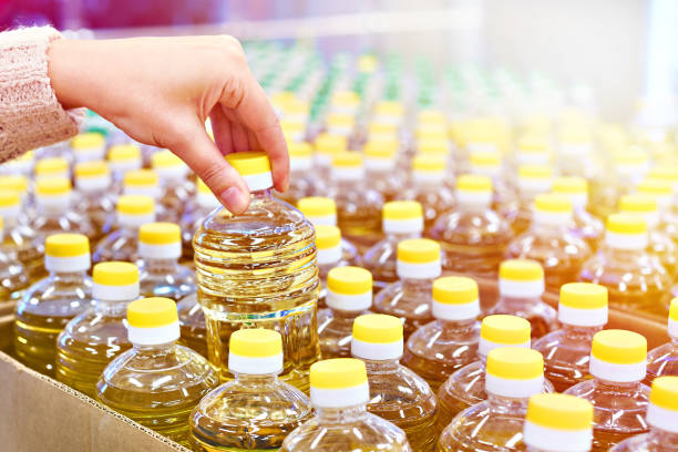 Buyer hand with sunflower oil packaging in the store